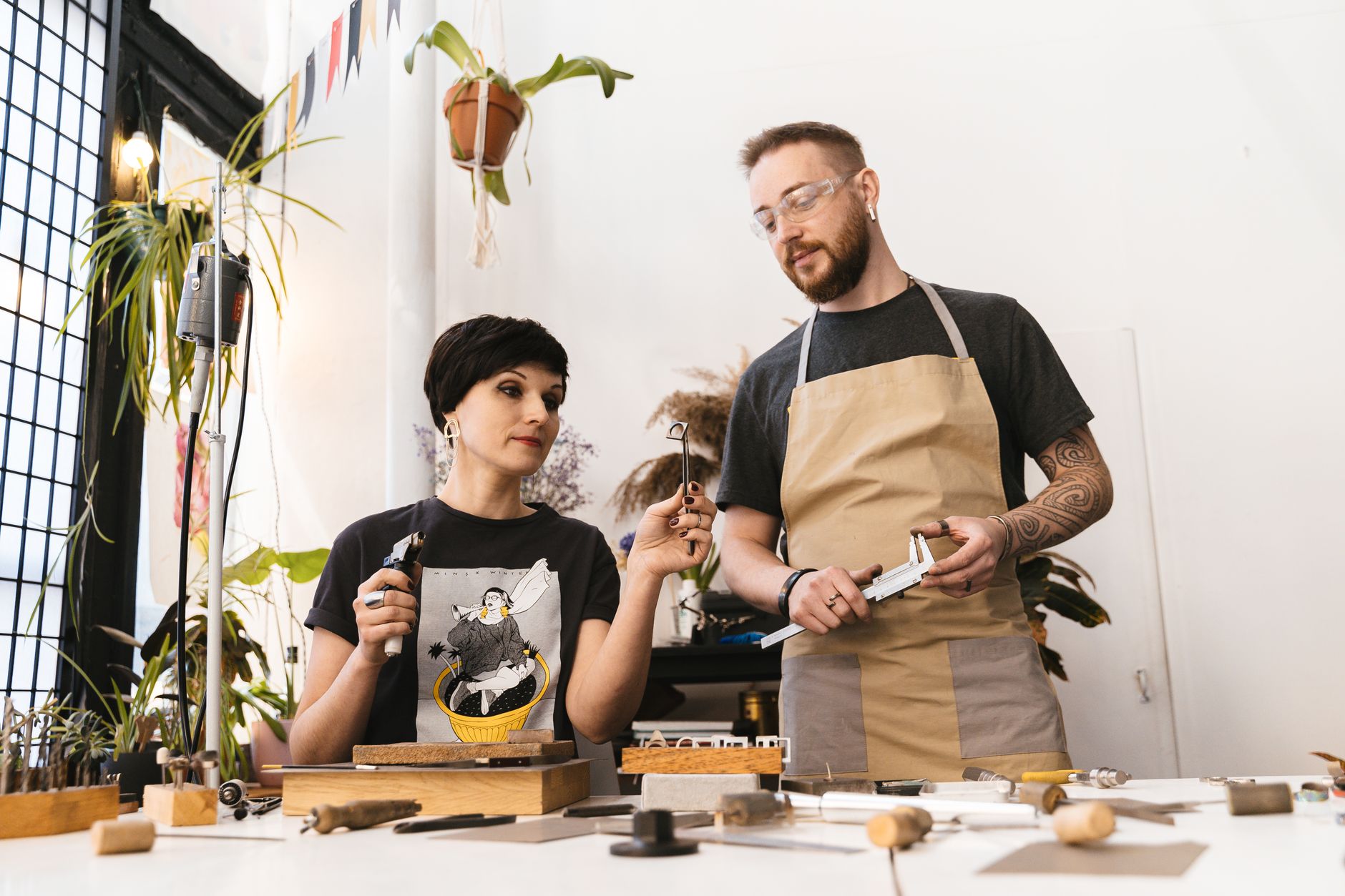 Two people wearing aprons behind a shop counter